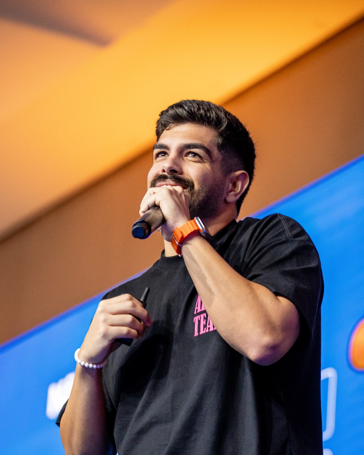 Yury Moza falando no palco de um evento, de microfone na mão